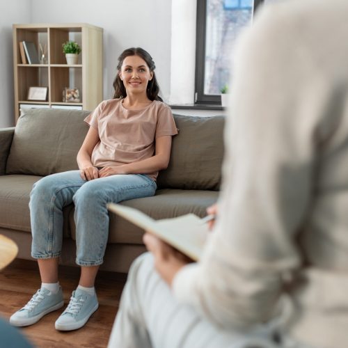 psychology, mental health and people concept - happy smiling young woman patient and woman psychologist at psychotherapy session